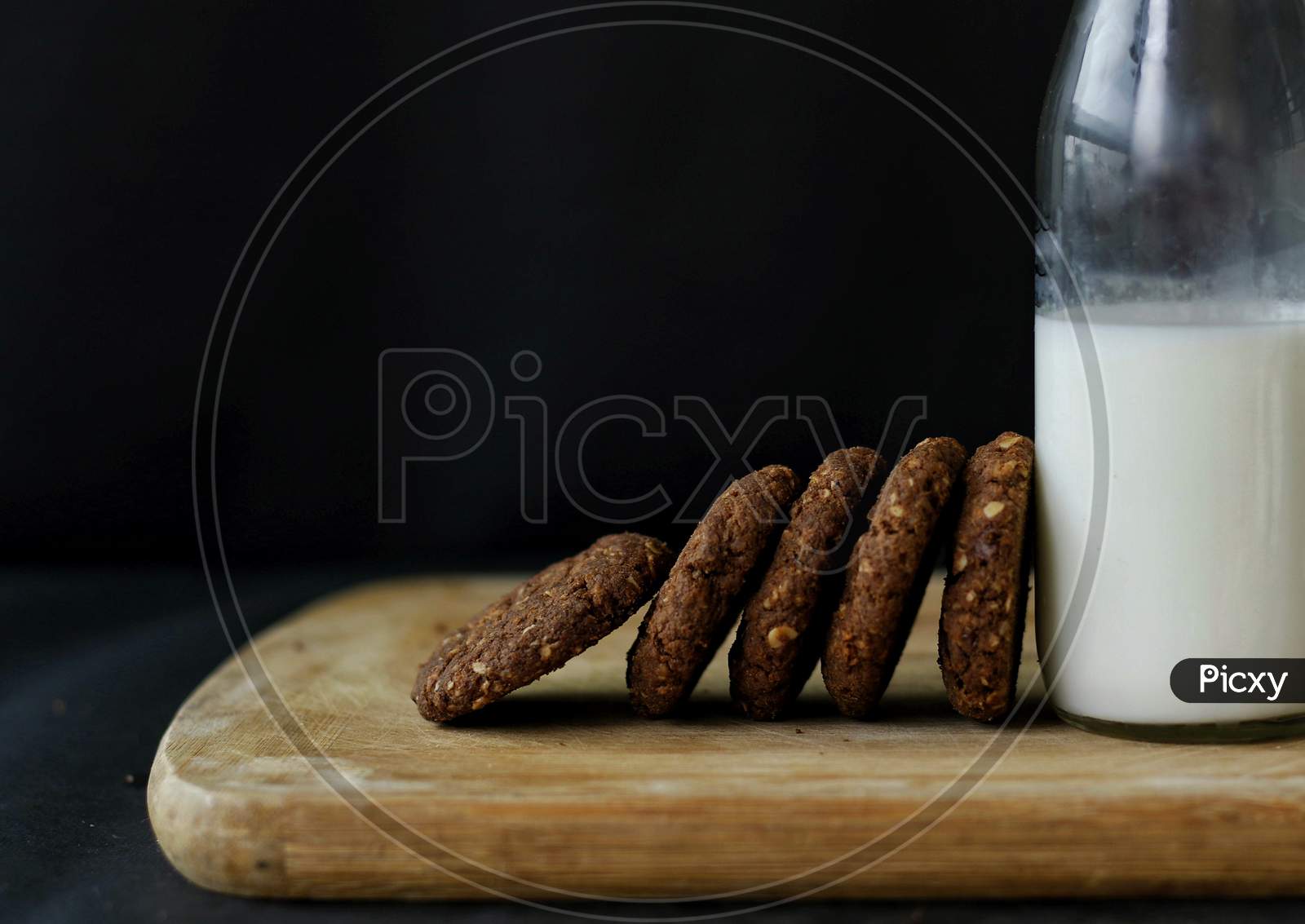 Chocolate And Oats Cookies Served With Milk Bottle On A Wooden Board