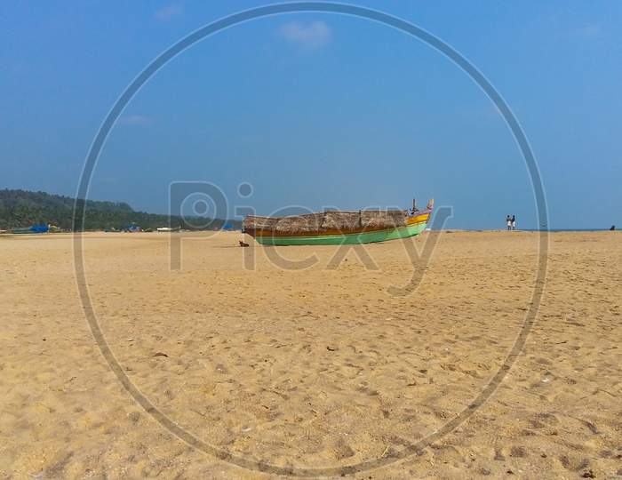 Landscape Image Of Sandy Azhimala Beach In Trivandrum, Kerala, India With A Parked Fishing Boat On Sand.