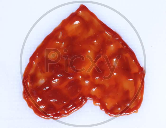 Ketchup in a shape of heart on white background