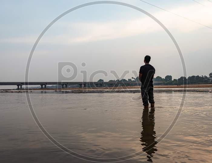 Man Feeling The True Nature Standing In The Flowing River With Bright Sky