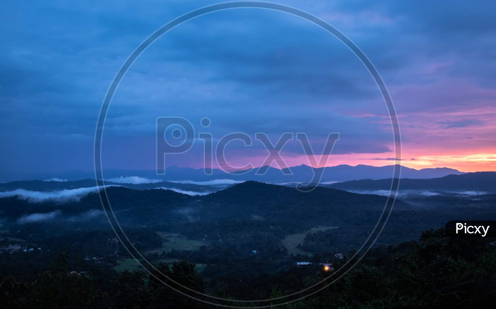 mountains range misty shadow with dramatic colorful sunset sky at dusk from flat angle