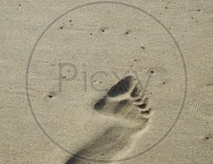 Footprints Of A Person On Sand In Beach.