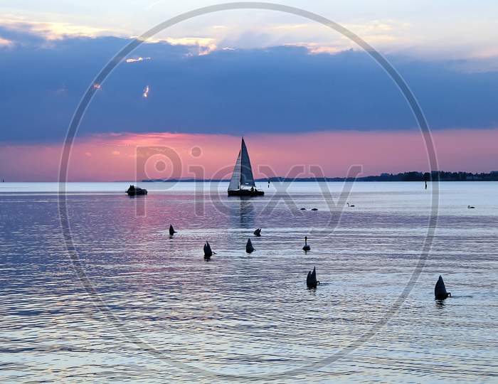 Beautiful Sunset Reflecting At Lake Constance With Boats And Swans