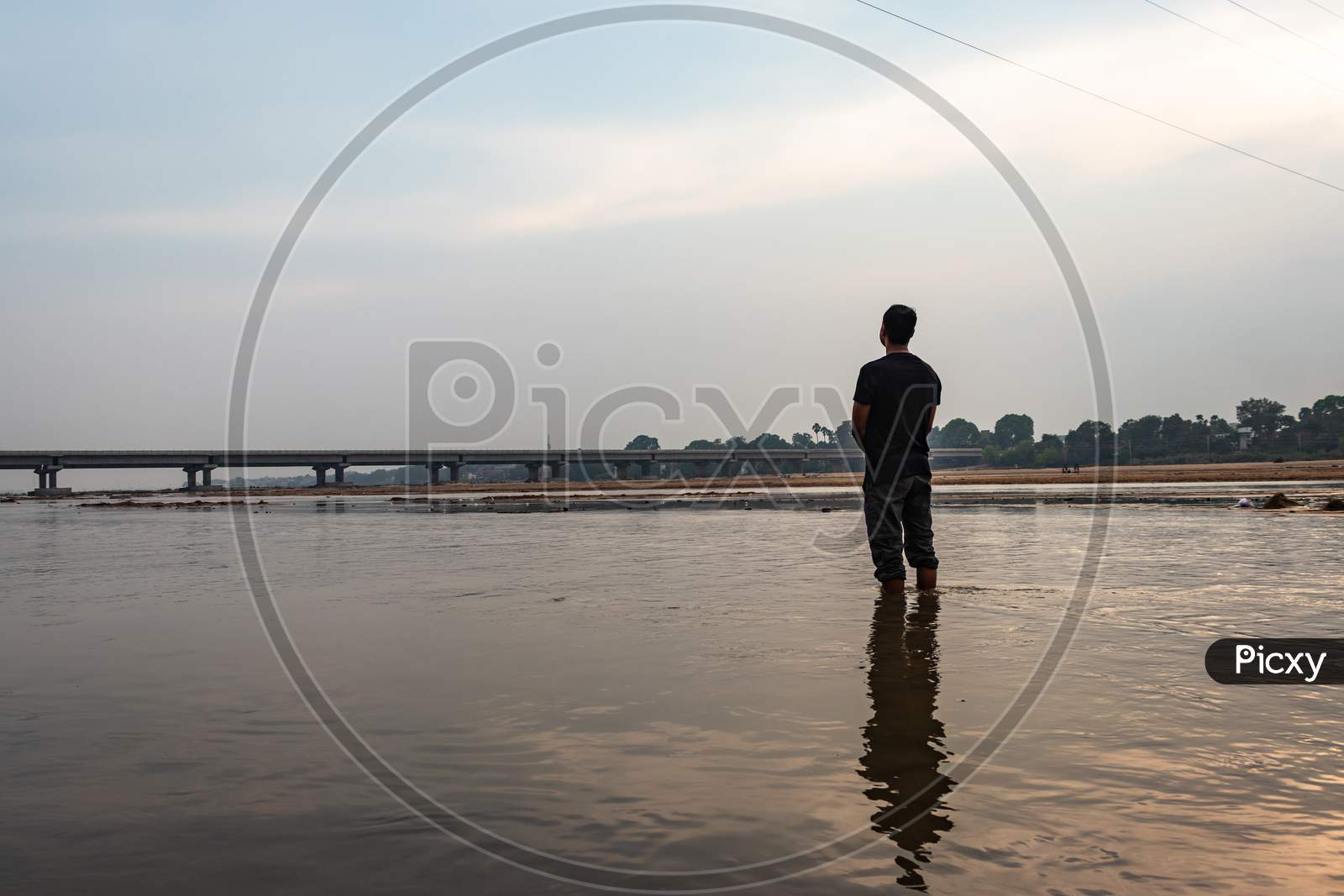 Man Feeling The True Nature Standing In The Flowing River With Bright Sky