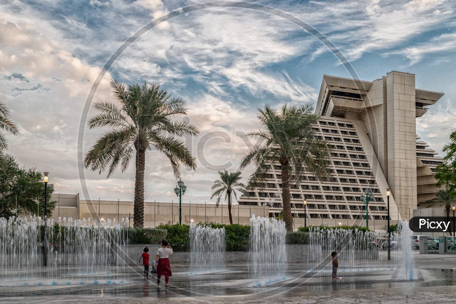 Sheraton Al Doha hotel exterior daylight view with fountain in foreground and clouds in sky in background