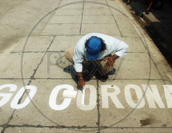 A man paints a message on a street after India ordered a 21- day nationwide lockdown to limit the spreading of coronavirus disease (COVID-19) in Mumbai, India on March 28, 2020.