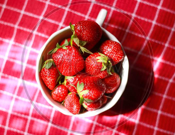 strawberry in a white bowl with red colour background