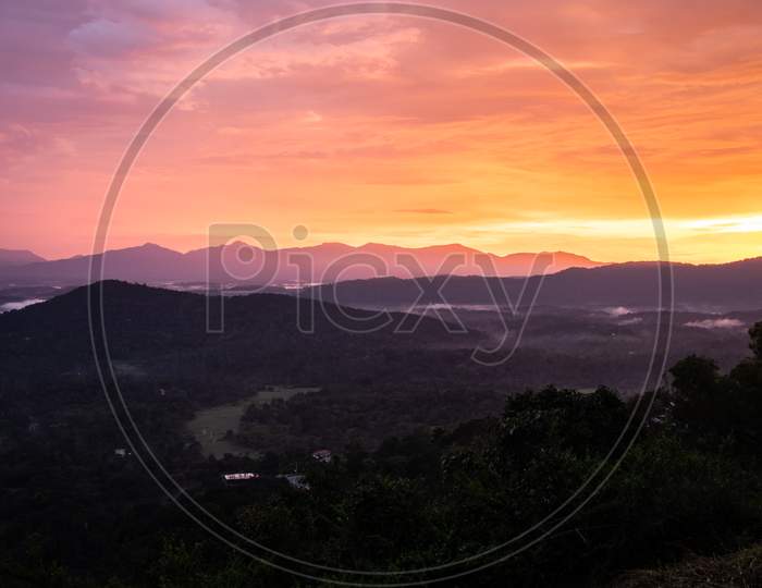 mountains range misty shadow with dramatic colorful sunset sky at dusk from flat angle