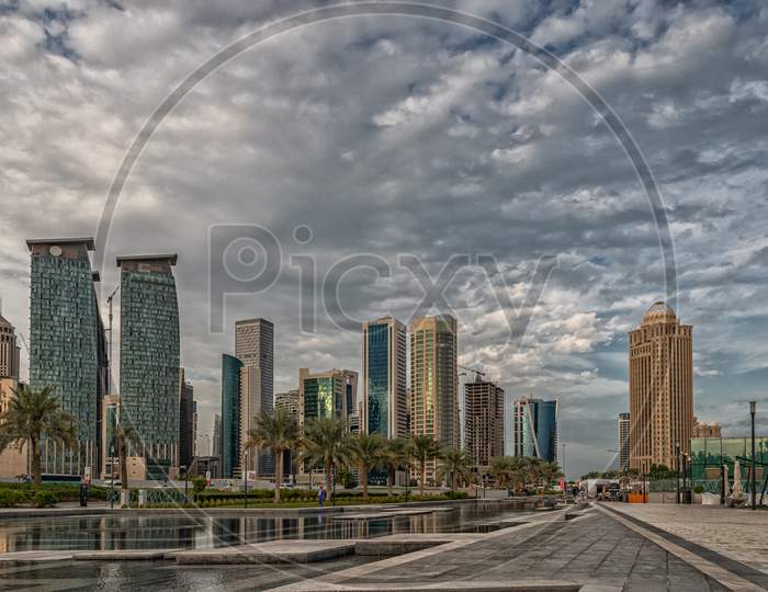 Doha, Qatar  Skyline daylight view from Sheraton park with reflection in the water and clouds in sky in background
