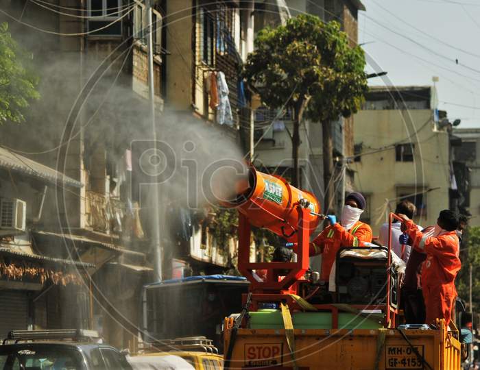 Workers use a blower to spray disinfectant to decontaminate a street during a 21-day nationwide lockdown to limit the spreading of coronavirus disease (COVID-19) in Mumbai, India, April 4, 2020.