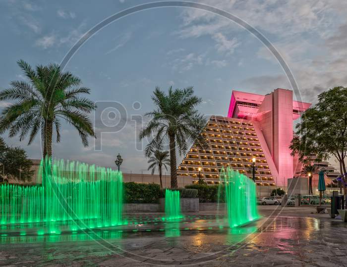 Sheraton Al Doha hotel  in Qatar exterior daylight view with illuminated  fountain in foreground and clouds in sky in background
