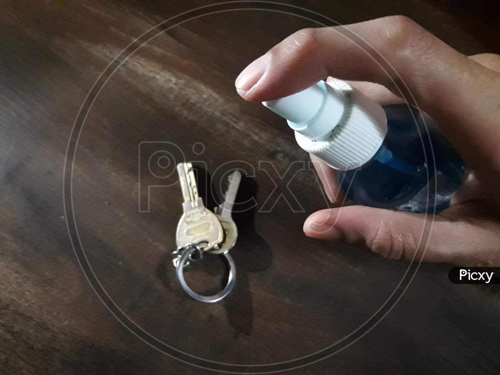Disinfecting The Keys With Sanitizer On A Wooden Table