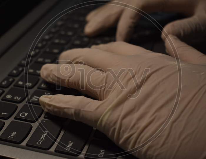 Hands in medical gloves on laptop.