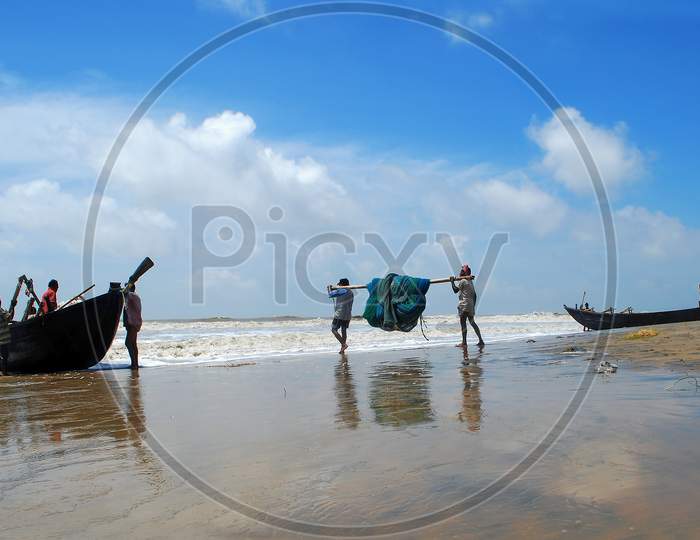 Fishermen carrying their colourful fishing net while going for fishing in the ocean.
