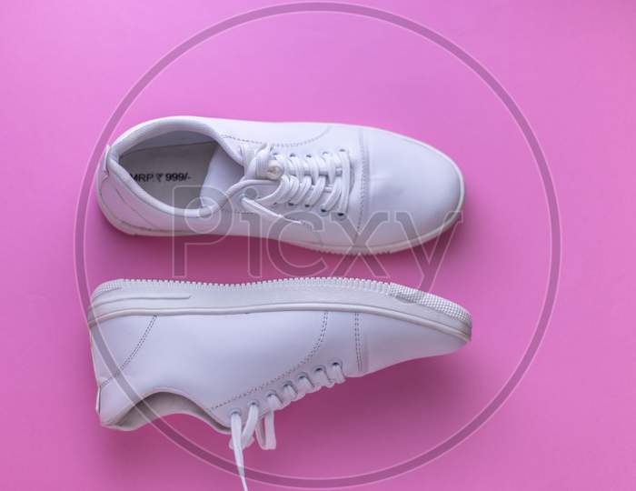 White sneakers on light colour background, flat lay top view minimal background.