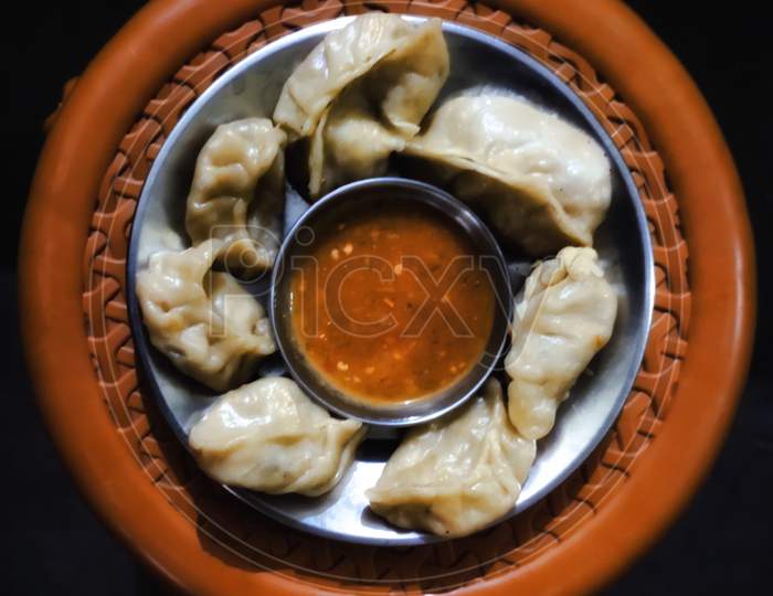 Home made steam Momos with sauce on black background