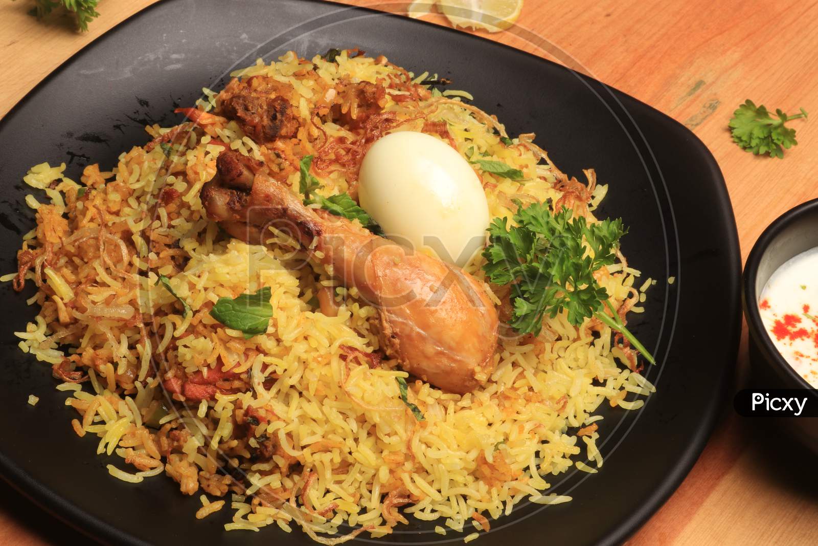 Indian Chicken Biryani served in a terracotta bowl with yogurt over white background. selective focus