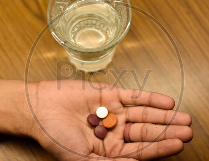corona antivirus pills in a boy hand on a wooden background