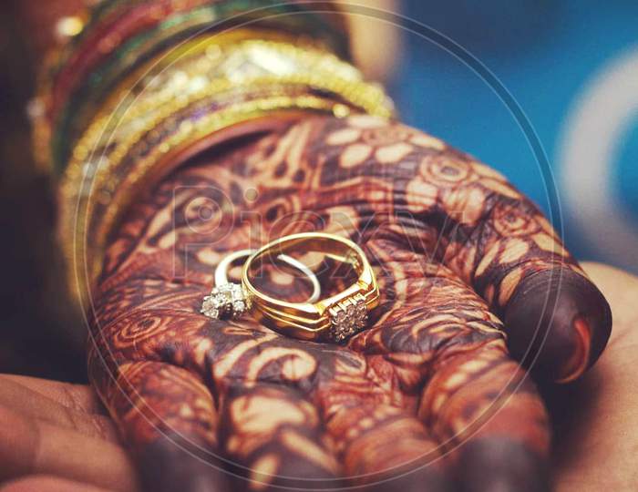 Engagement rings in hands of bride and groom