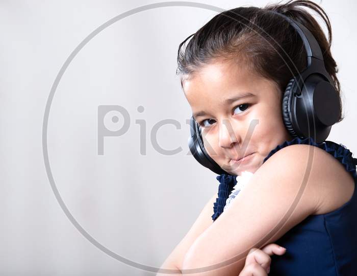 Cute Little Girl With Headphones Giving Cute Expression Toward The Camera