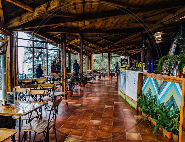 Shimla, Himachal Pradesh,India-January 2019:Cafe  in dark forest , Highest cafe in Shimla,Hill station in Himachala pradesh, empty table chairs on floor, room covered with glass surrounded by trees