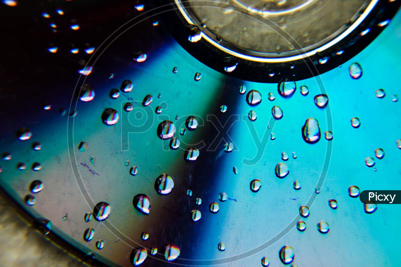 Water drops on disk, Selective focus on water drops with blurred disk background ,Vibrant color reflection on water drops, scratches on disk CD/DVD