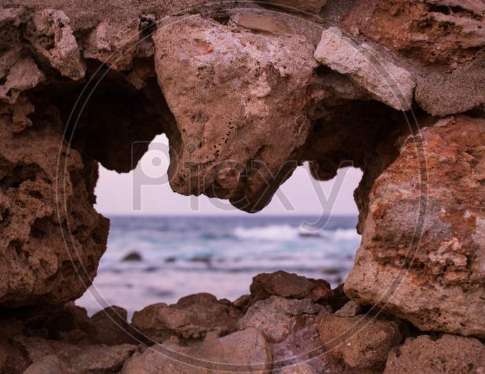 View to the sea through a hole on the stone wall of the fortress in Crete island