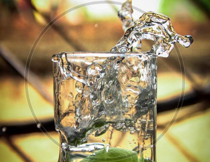 Fresh green lemon in water splash, Lemon water splash in glass, Refreshment drink in summer