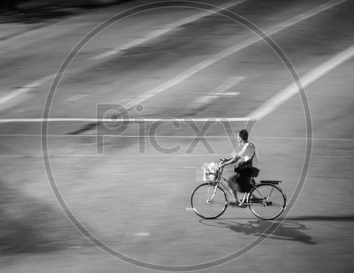 A man riding his bicycle in an empty road