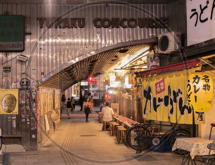 Night View Of Yurakucho Concourse Underpass Under The Railway Line Of The Station Yurakucho. Japanese Noodle Stalls And Sake Bars Revive The Nostalgic Years Of Showa Air With Old Posters And Placards Glued To The Walls Of The Tunnel.