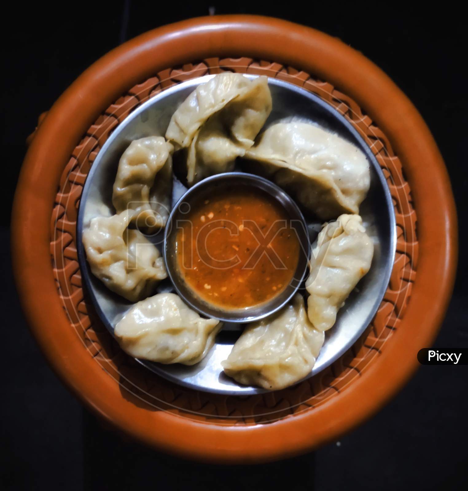 Home made steam Momos with sauce on black background