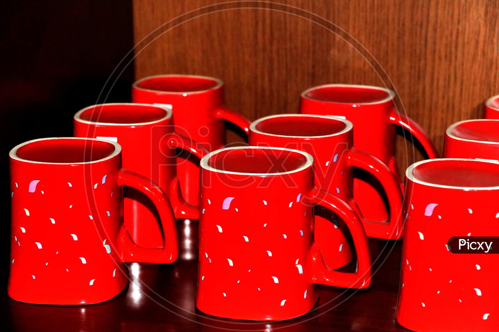 Red color coffee mug for the refreshment is waiting at showcase