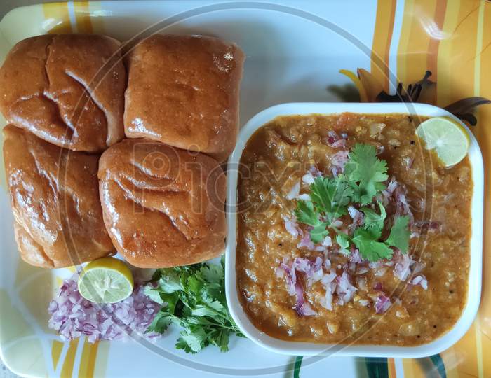 Pavbhaji in a plate. Pavbhaji with chopped onion and lemon slice. Pav bhaji breakfast dish. Indian local dish pavbhaji. Bread and vegetables in a plate.