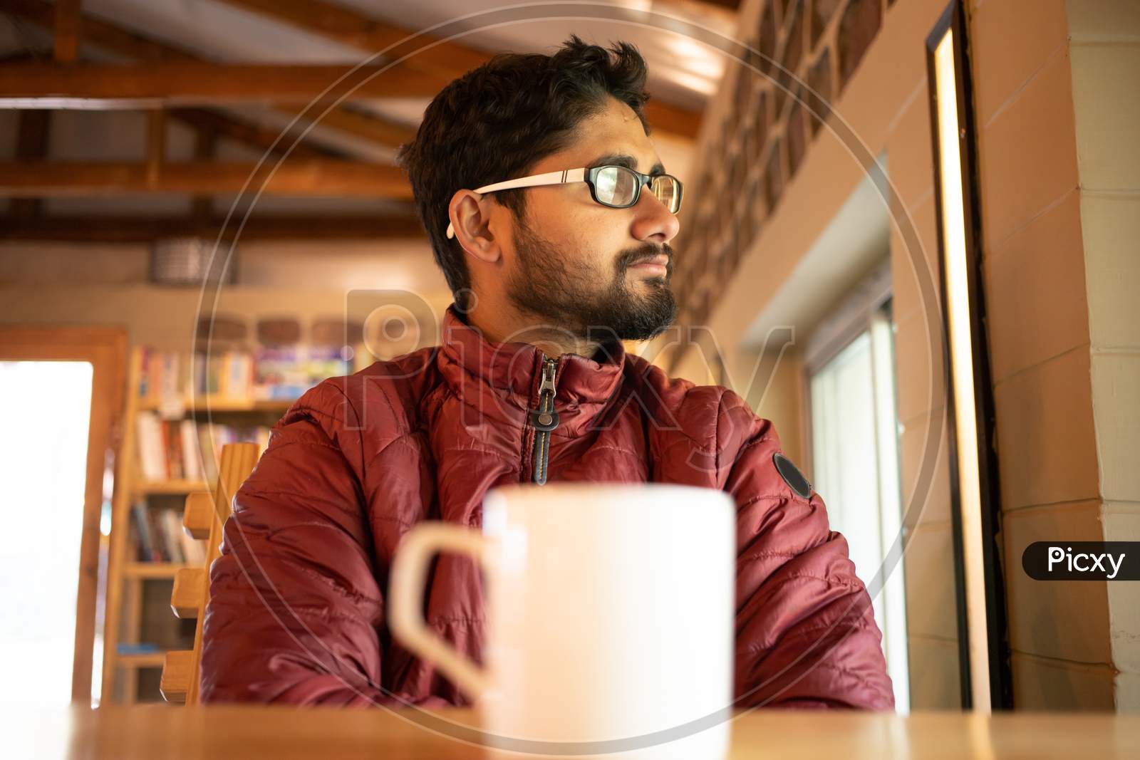 Young man sitting alone in a coffee shop in thinking while taking Coffee