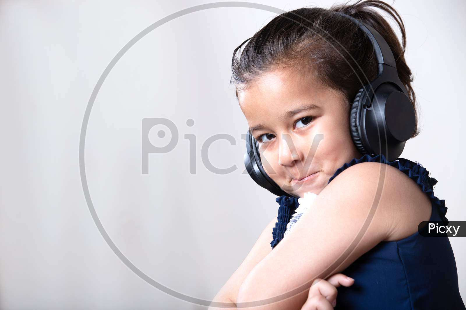 Cute Little Girl With Headphones Giving Cute Expression Toward The Camera