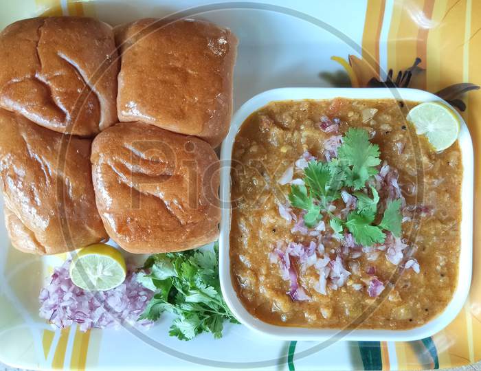 Pavbhaji in a plate. Pavbhaji with chopped onion and lemon slice. Pav bhaji breakfast dish. Indian local dish pavbhaji. Bread and vegetables in a plate.