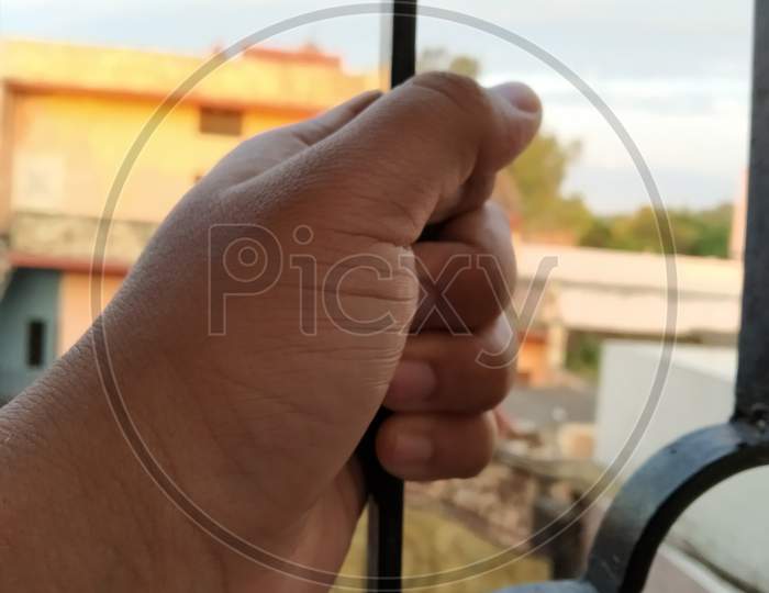 Window view with hand holding iron rod
