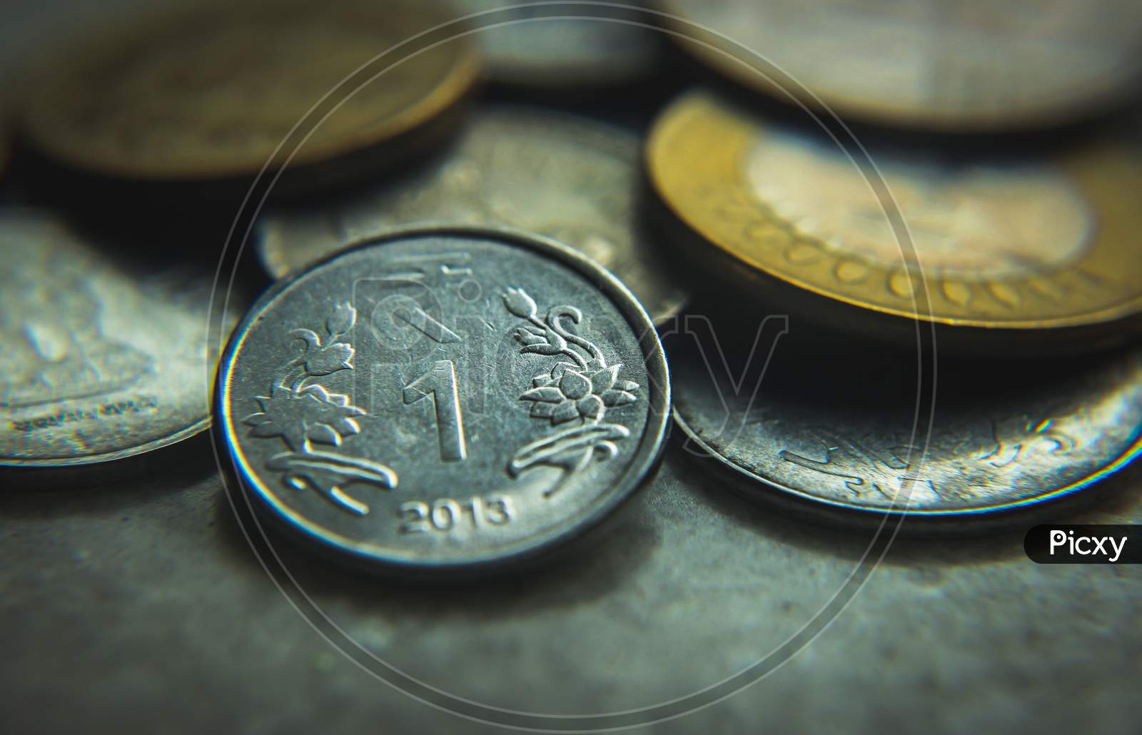 Coins of Indian currency rupee (INR) . Golden five rupee , ten rupee coins and silver one rupee coins. Selective focus on coins with blurred background