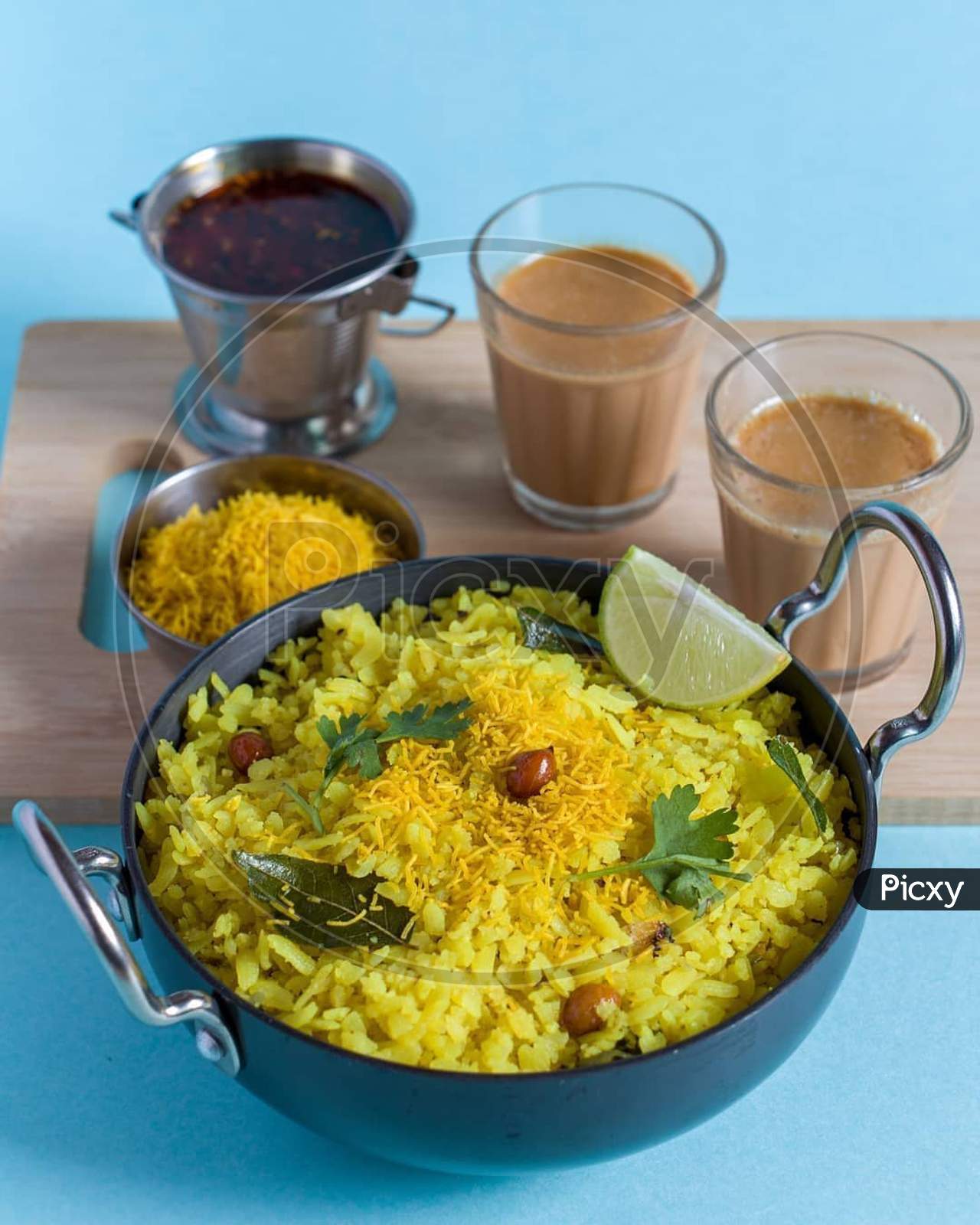 Indian breakfast poha served in bowl with lemon and tea