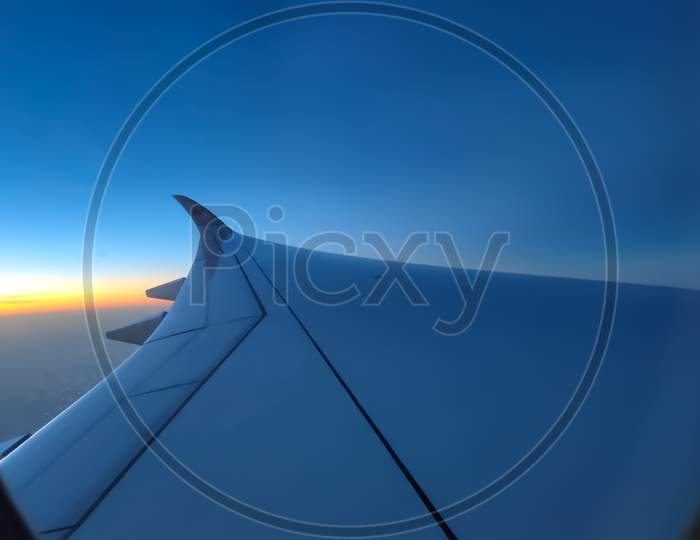 View of a wing of a plane with blue sky from window
