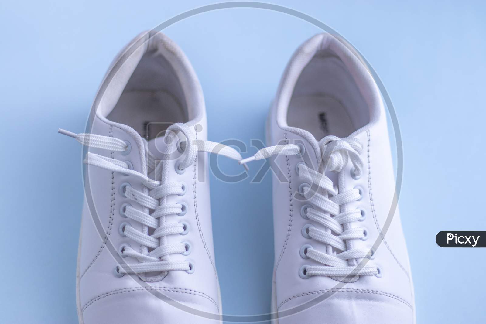 White sneakers on light blue colour background, flat lay top view minimal background.
