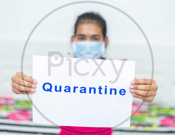 Young Girl Wearing Surgical Protection Mask Holding White Board With Text Quarantine. Stay At Home Concept.