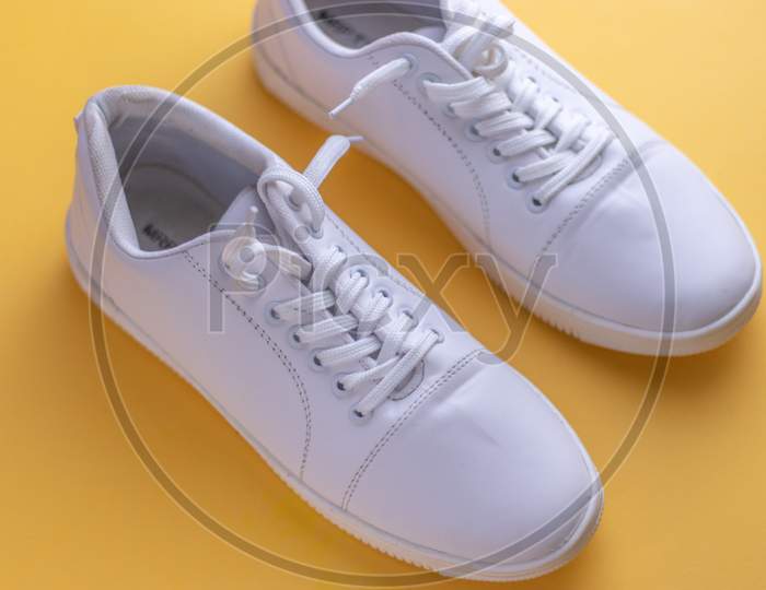 White sneakers on light colour background, flat lay top view minimal background.