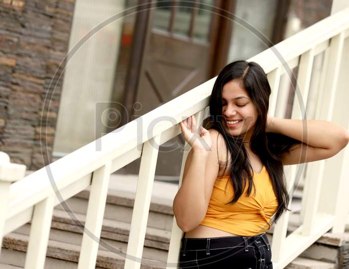 Young teenage girl Lifestyle shot with Expression outside of house with Stair case railing