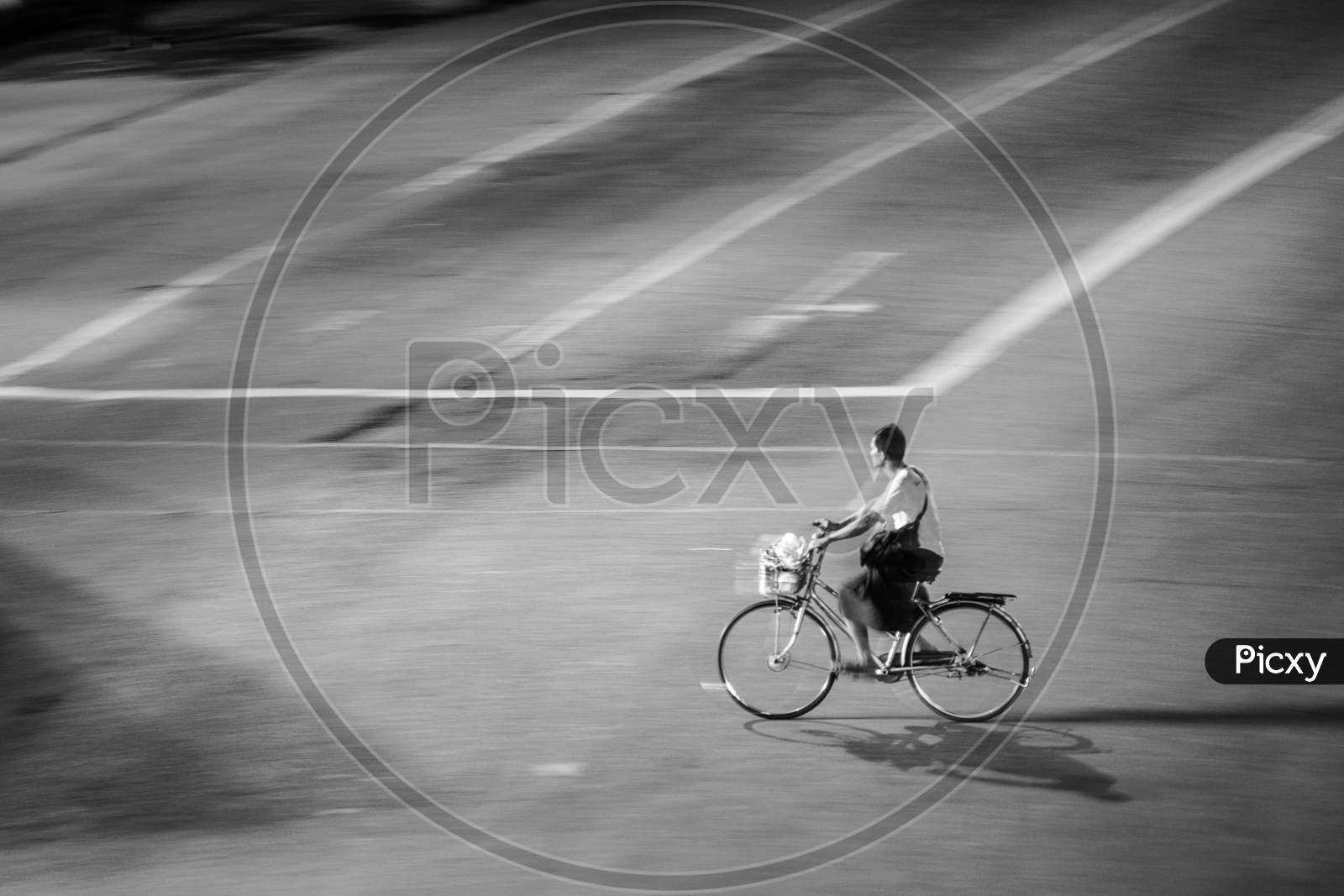 A man riding his bicycle in an empty road