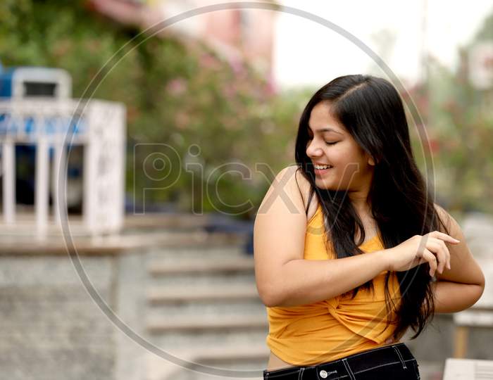 Young Teenage Girl Smiling In Western Wear In Public Place. Indian Girl Natural Expression Shoot