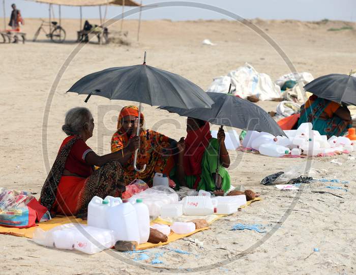 Women Taking Shelter Under Umbrellas on a Hot Day At The Bank Of Ganga River in Prayagraj on May 30,2020