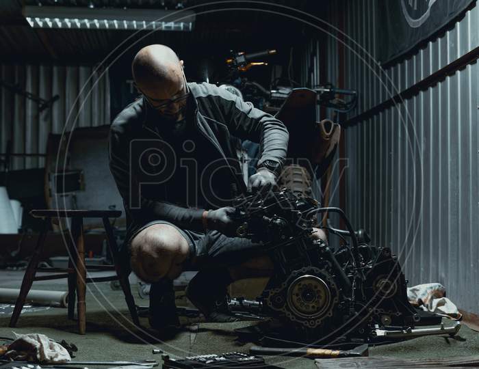 Man repairing his motorcycle engine in the garage.