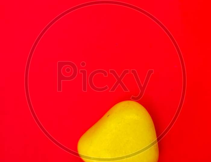 Yellow Color Natural Pebbles Isolated On Red Background With Space For Copy Text And Words. Multi Color Natural Pebbles Stone. Yellow Color Stone Isolated. Colorful Sea Stones