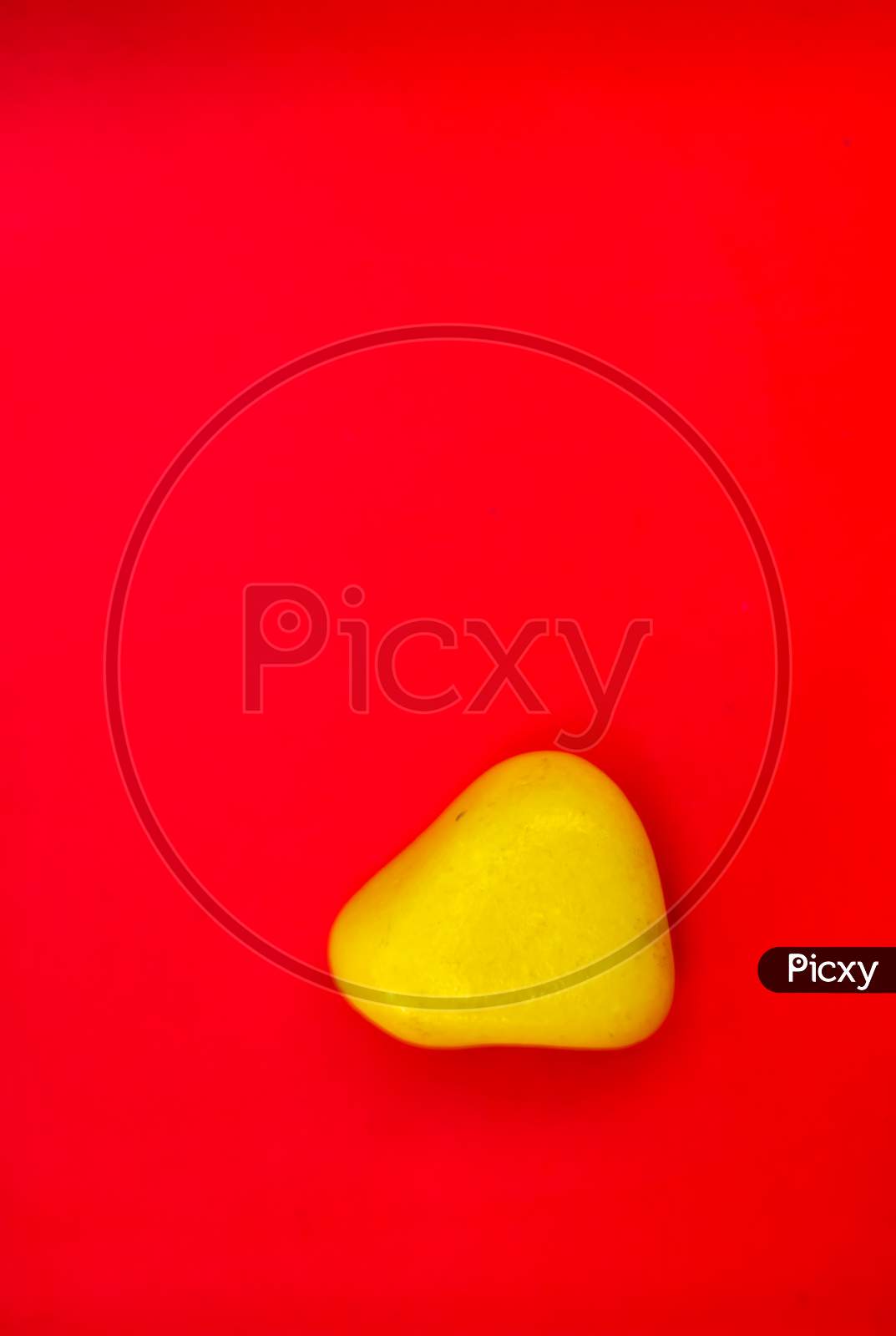 Yellow Color Natural Pebbles Isolated On Red Background With Space For Copy Text And Words. Multi Color Natural Pebbles Stone. Yellow Color Stone Isolated. Colorful Sea Stones